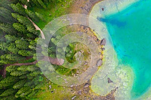 Aerial view of turquoise blue water of lake Carezza in Alps Dolomites. Lago di Karersee near fir tree forest photo