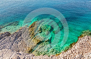 Aerial view of turquoise calm sea against rocks. Wonderful beauty wild beach with stony rocky shore, shallow sea water. Beautiful