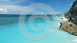 Aerial view of turquoise ocean with tropical sandy beach and rocks