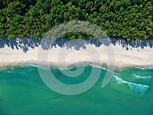 Aerial view on turquoise ocean water with clean empty sand beach and forest