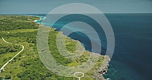 Aerial view of turquoise salt water lake at green tropic trees. Buildings, road at greenery valley