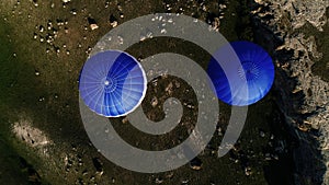 Aerial view of two blue hot air balloons flying above rural roads and green trees and fields. Shot. Flying in the sky