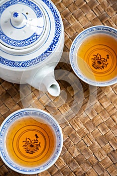 Aerial view of two blue teacups with teapot, selective focus, on a braided tray, vertically,