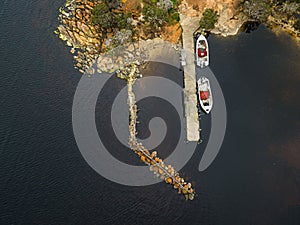 Aerial view of two boats near a wooden dock on a rocky shoreline