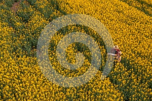 Aerial view of two farmer inspecting damaged crops in blooming rapeseed field