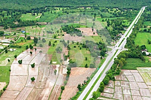 Aerial view of two-lane road through paddy fields and mountain range in rainy