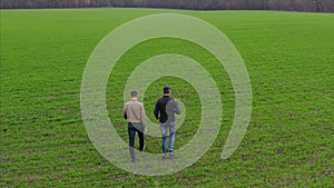 Aerial view of two male farmers walking through a field