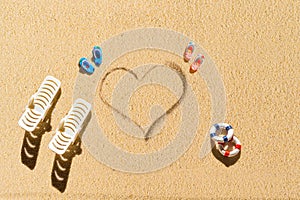 Aerial view of two pair of flip flops, sunbed in shape of heart on sandy tropical beach. Valentines day. Holiday concept. Creative