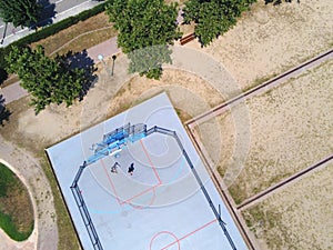 Aerial view of two unrecognizable teen playing basket on a urban court in sunny day