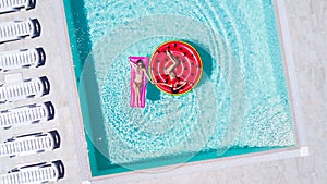 Aerial view of two women floating on inflatable mattresses relaxing in the swimming pool. Summer vocation