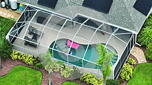 Aerial view of typical contemporary american private house with outside lanai enclosure covering big swimming pool