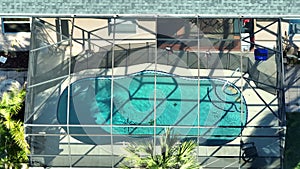 Aerial view of typical contemporary american private house with outside lanai enclosure covering big swimming pool