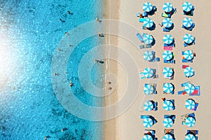 Aerial view of umbrellas on white sandy beach, blue sea at sunset