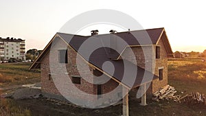 Aerial view of unfinished house with wooden roof structure covered with metal tile sheets under construction.