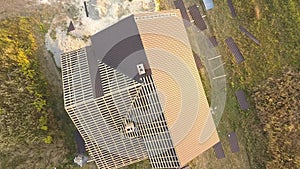 Aerial view of unfinished house with wooden roof structure covered with metal tile sheets under construction.