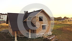 Aerial view of unfinished house with wooden roof structure covered with metal tile sheets under construction.