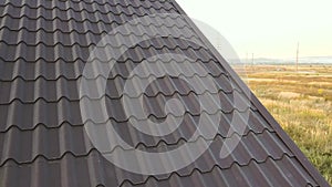 Aerial view of unfinished house with wooden roof structure covered with metal tile sheets under construction.