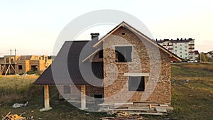 Aerial view of unfinished house with wooden roof structure covered with metal tile sheets under construction.