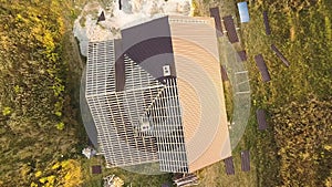 Aerial view of unfinished house with wooden roof structure covered with metal tile sheets under construction.