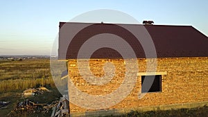 Aerial view of unfinished house with wooden roof structure covered with metal tile sheets under construction.