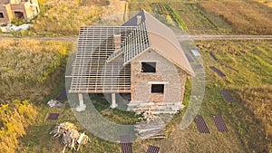 Aerial view of unfinished house with wooden roof structure covered with metal tile sheets under construction.