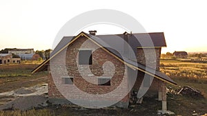 Aerial view of unfinished house with wooden roof structure covered with metal tile sheets under construction.