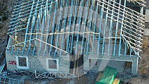 Aerial view of unfinished residential house with metal roof frame structure under construction in Florida suburban area