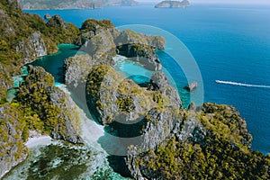 Aerial view of a unique blue lagoon surrounded by jagged limestone cliffs located on tropical Miniloc Island, El Nido