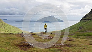 Aerial view of unrecognizable man looking at the panorama, islands, ocean, green mountain and rock cliffs.Impressions of