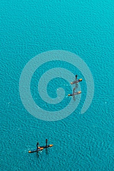 Aerial view of unrecognizable people stand up paddle boarding