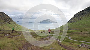 Aerial view of unrecognizable woman looking at the panorama, islands, ocean, green mountain and rock cliffs.Impressions