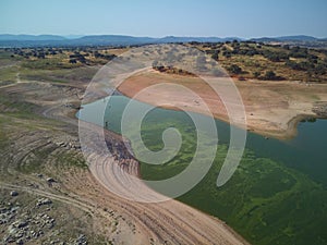 Aerial view of the ValdecaÃ±as reservoir, with green water from the algae and natural lines of the descent of the water. Natural