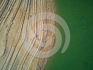 Aerial view of the ValdecaÃ±as reservoir, with green water from the algae and natural lines of the descent of the water. Natural