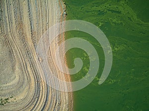 Aerial view of the ValdecaÃ±as reservoir, with green water from the algae and natural lines of the descent of the water. Natural