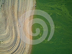 Aerial view of the ValdecaÃ±as reservoir, with green water from the algae and natural lines of the descent of the water. Natural