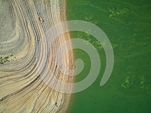 Aerial view of the ValdecaÃ±as reservoir, with green water from the algae and natural lines of the descent of the water. Natural