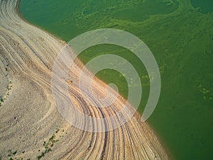 Aerial view of the ValdecaÃ±as reservoir, with green water from the algae and natural lines of the descent of the water. Natural