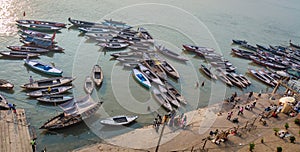 Aerial view of Varanasi Ganges river ghat with multicolored wooden boats and tourists.