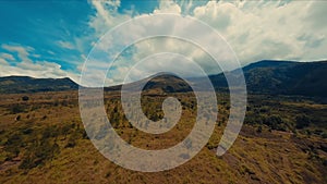 Aerial view of a vast, undulating landscape with mountains under a cloudy sky