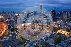 Aerial view of Victory Monument with car light trails on busy street road. Roundabout in Bangkok Downtown Skyline. Thailand.