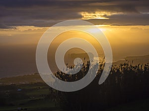 Aerial view of Vila Franca do Campo town volcanic islet during orange sunset with clouds, contre-jour light, Sao Miguel
