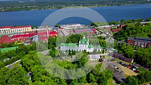 Aerial view of a village located by the river shore. Clip. Flying above summer green nature and buildings.