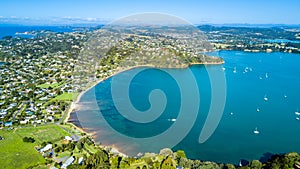 Aerial view on a vineyard on the shore of sunny harbour with residential suburbs on the background. Waiheke Island, New Zealand