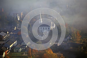 Aerial view of Waitsfield, VT in fog with church steeple on Scenic Route 100 in Autumn