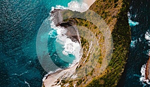 an aerial view of the water next to the rock and some trees