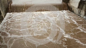 Aerial view of the water released from the concrete dam`s drainage channel as the overflow in the rainy season. Top view of turbid