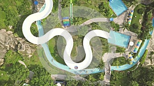 Aerial view water slide in amusement aquapark. People having fun riding on slides in outdoor water park. Summer activity