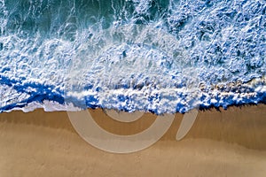 Aerial view of a wave breaking at the shore of the Comporta Beach