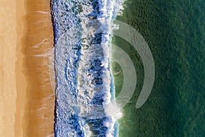 Aerial view of a wave breaking at the shore of the Comporta Beach