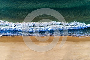 Aerial view of a wave breaking at the shore of the Comporta Beach